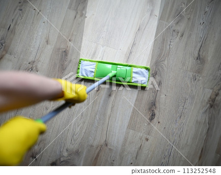 Male hand with yellow protective gloves hold green plastic mop Male hand with yellow protective gloves hold green plastic mop 113252548