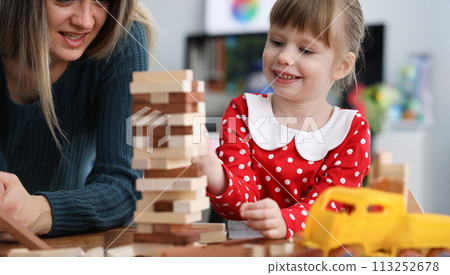 Mom and daughter are sitting at table playing game 113252678