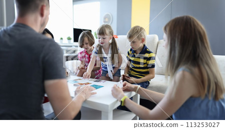 Team of three children and team of three adults play board games at home. 113253027