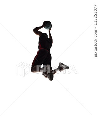 Slam dunk. Silhouette of young man, basketball player in motion during game throwing ball into basket isolated on white background 113253077