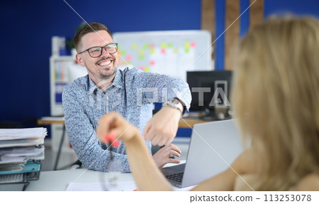 Cheerful man in glasses show client watch on his hand at workplace. Cheerful man in glasses show client watch on his hand at workplace. 113253078