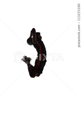 Dynamic image of concentrated young man, basketball player in motion, throwing ball in jump, playing isolated on white background. Silhouette Dynamic image of concentrated young man, basketball player in motion, throwing ball in jump, playing isolated on white background. Silhouette 113253100
