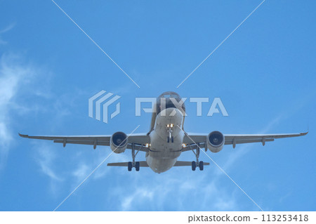 A jet plane flying over Fukuoka Airport under a blue sky 113253418