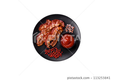Delicious fresh fried bacon with salt and spices on a dark background Delicious fresh fried bacon with salt and spices on a dark background 113253841