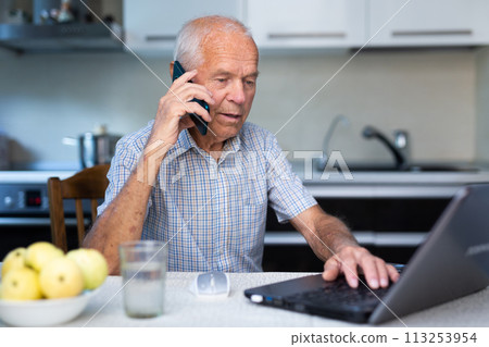 Senior man using laptop and talking on phone 113253954