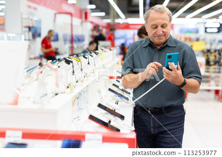 Elderly man chooses mobile phone in store 113253977