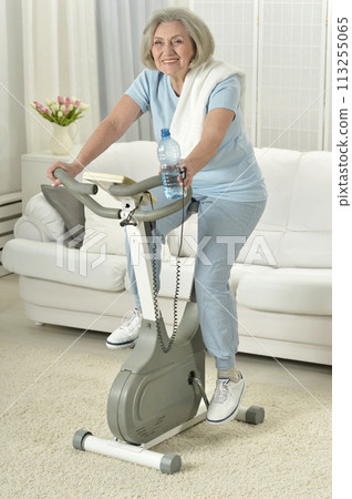 Elderly woman exercising on an exercise bike Elderly woman exercising on an exercise bike 113255065