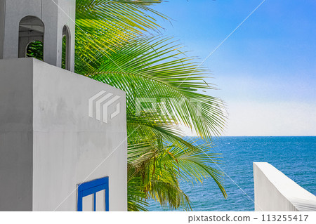 View of the decoration of the white chapel, which stands in the shade of a palm tree on the seashore 113255417