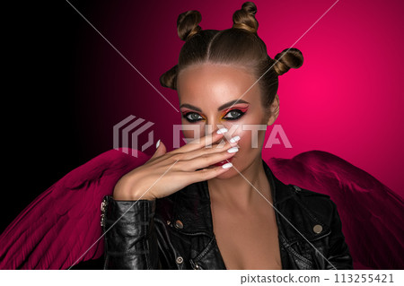 Portrait of a young sassy girl with blond hair in the studio on a pink background. 113255421