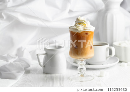 Iced caramel latte topped with whipped cream and caramel sauce. 113255680