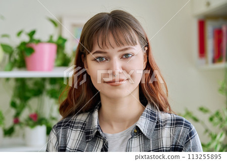 Portrait of smiling female teenager looking at camera in home 113255895