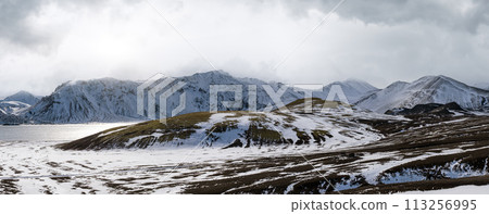 Season change in the Icelandic highlands.  Colorful Landmannalaugar mountains under snow cover in autumn. Frostastadavatn lake at the foot of the mountains. 113256995