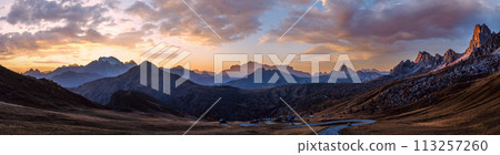 Sun glow in evening hazy sky. Mountain panoramic peaceful view from Giau Pass. Sun glow in evening hazy sky. Mountain panoramic peaceful view from Giau Pass. 113257260