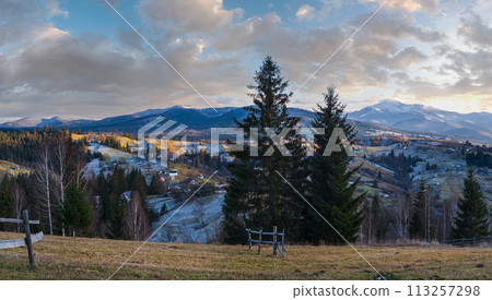 Late autumn mountain pre sunset scene with snow covered tops in far. Picturesque traveling, seasonal, nature and countryside beauty concept scene. Carpathians, Ukraine. 113257298