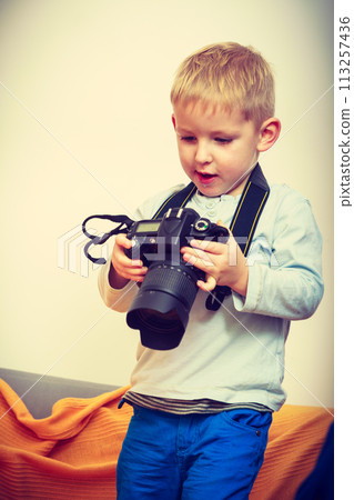 Kid playing with big professional digital camera Kid playing with big professional digital camera 113257436