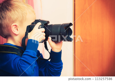 Kid playing with big professional digital camera 113257586