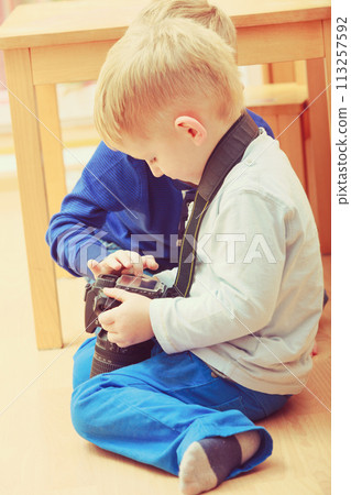 Kid playing with big professional digital camera 113257592