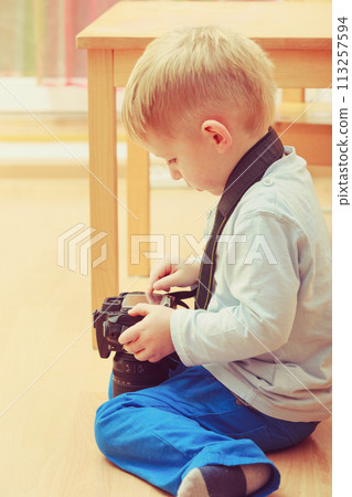 Kid playing with big professional digital camera Kid playing with big professional digital camera 113257594
