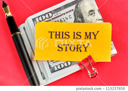 Business and my story concept. Text This is my story on a sticker lying on dollar bills on a red background, next to a fountain pen Business and my story concept. Text This is my story on a sticker lying on dollar bills on a red background, next to a fountain pen 113257850