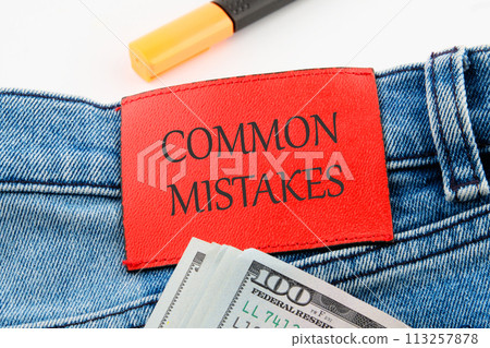 Common mistakes, text on the leather insert of jeans with dollar bills sticking out Common mistakes, text on the leather insert of jeans with dollar bills sticking out 113257878