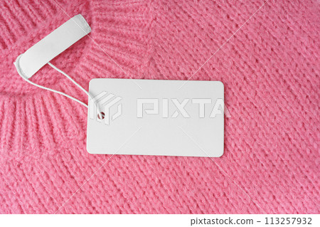 Blank clothing tag and inner label on neck of pink knitted sweater background 113257932