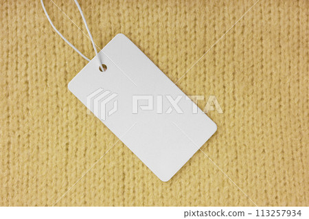 Template of blank clothing label, price tag on yellow knitted sweater background 113257934