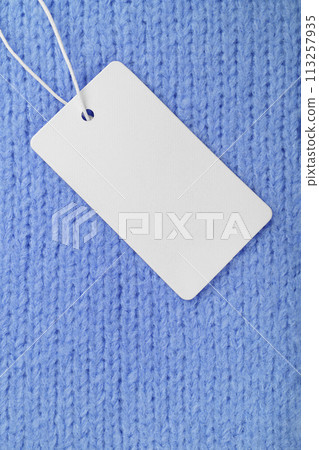 Template of blank clothing label, price tag on blue knitted sweater background 113257935