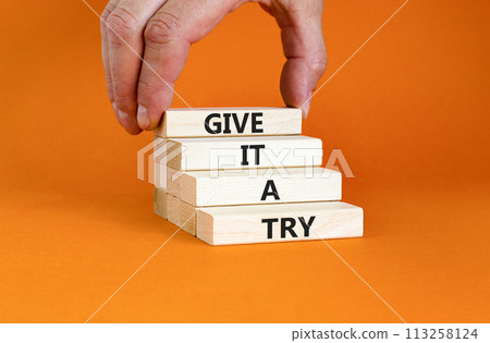 Give it a try symbol. Concept word Give it a try on beautiful wooden block. Beautiful orange table orange background. Businessman hand. Business give it a try concept. Copy space. 113258124