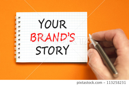 Branding and your brand story symbol. Concept words Your brands story on beautiful white note. Beautiful orange background. Businessman hand. Business branding your brand story concept. Copy space. 113258231
