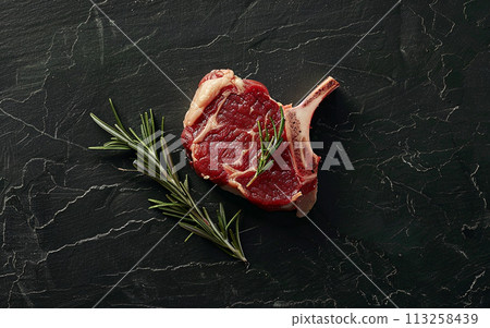 Raw Steak with Rosemary on Dark Slate Raw Steak with Rosemary on Dark Slate 113258439