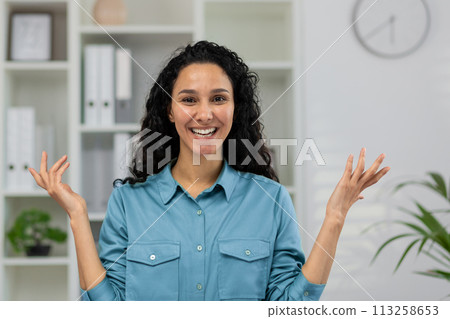 Perplexed professional woman on a video call, gesturing in confusion during an online meeting at a modern home office. 113258653