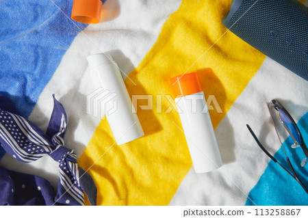 Sunscreen lotion on beach towel. Care products summer accessories Sunscreen lotion on beach towel. Care products summer accessories 113258867