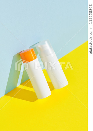 Sunscreen lotion on blue yellow background with copy space. Body care beauty treatment concept Sunscreen lotion on blue yellow background with copy space. Body care beauty treatment concept 113258868