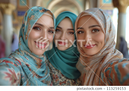 Young smiling islamic women friends wearing colorful abaya and taking selfie together 113259153