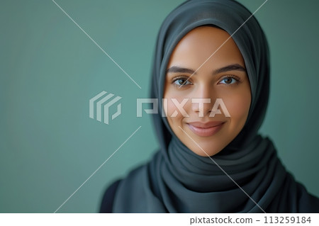 Portrait of young smiling Arabian muslim woman in abaya on green background with copy space 113259184