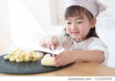 A girl cutting a banana with a knife A girl cutting a banana with a knife 113259781