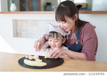 一個女孩幫她媽媽做飯 一個女孩幫她媽媽做飯 113259793