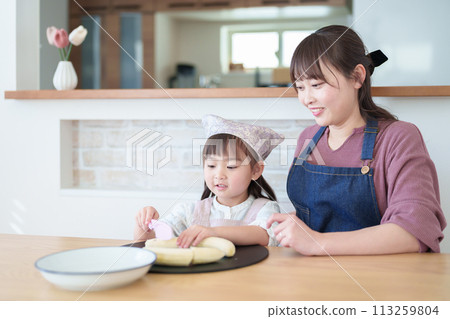 一個女孩幫她媽媽做飯 113259804