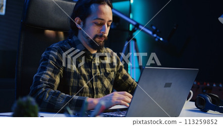 Portrait of smiling freelancer working from home, typing on laptop, surfing the net. Joyful remote employee browsing on digital device, sending emails to customers, camera B 113259852