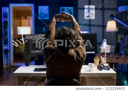 Programmer stretching body limbs after securing company servers from virus attacks all day. Fatigued IT remote employee relaxing tense muscles at desk after building firewalls protecting data 113259953