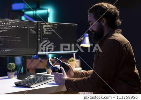 Programmer putting headphones on while implementing security measures to protect company systems and data. IT admin listening music, testing and debugging code for software applications 113259956