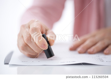 Hand of a middle-aged woman stamping a power of attorney Hand of a middle-aged woman stamping a power of attorney 113260504