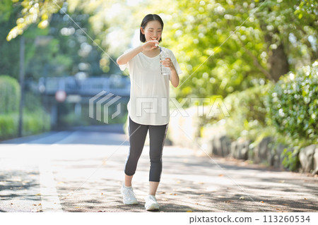 穿著運動服的年輕女子用塑膠瓶喝水 113260534
