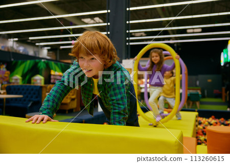 Happy children passing road of obstacles on indoor playground Happy children passing road of obstacles on indoor playground 113260615
