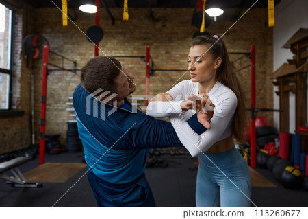 Young woman doing self defense training with personal coach at gym Young woman doing self defense training with personal coach at gym 113260677