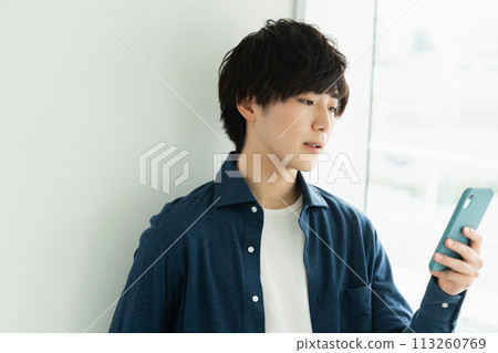 操作智能手機的一個年輕人 113260769