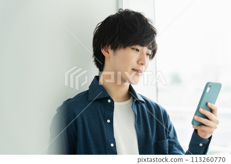 A young man operating a smartphone A young man operating a smartphone 113260770