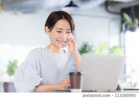 一位美麗的微笑女士在漂亮的辦公室或咖啡館裡用電腦工作 113260895