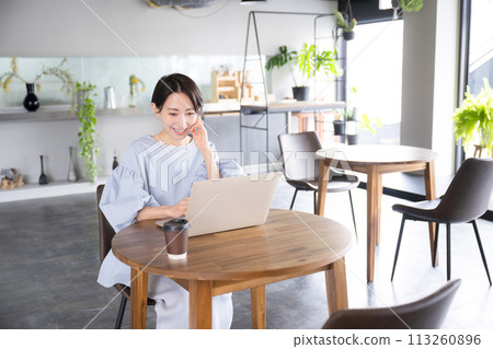 A beautiful smiling woman using a computer in a beautiful office or cafe 113260896