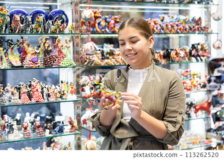 Young woman looking at bull figurine at souvenir market Young woman looking at bull figurine at souvenir market 113262520